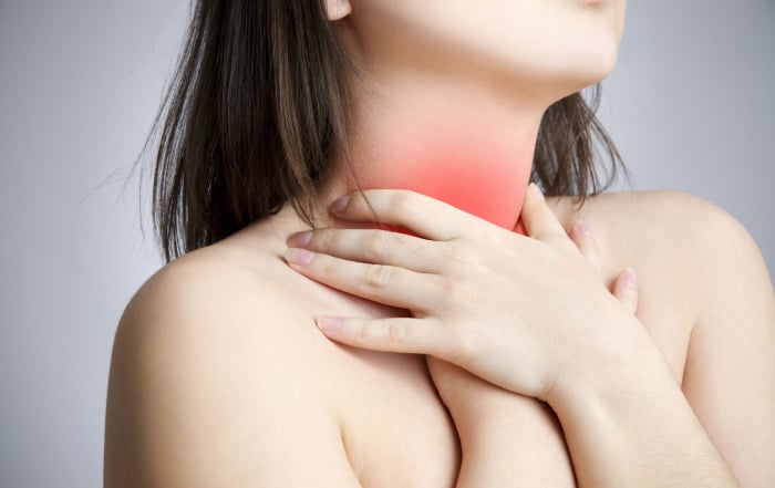 woman with acid reflux grasping throat in San Antonio TX