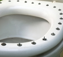 hemorrhoid pain symbolized by metal circle sharp buttons on the top of toilet